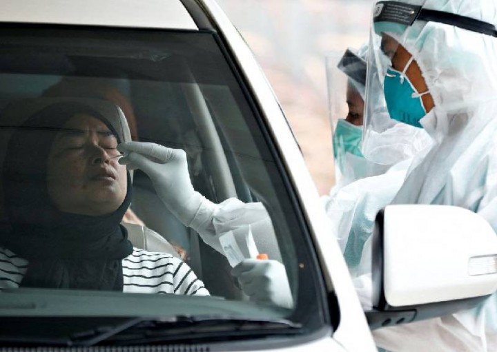 Seorang petugas kesehatan yang mengenakan alat pelindung diri (APD) mengambil sampel swab untuk pengujian penyakit virus corona (Covid-19) di tempat pengujian drive-through di Jakarta, Indonesia, pada 16 Desember 2021.