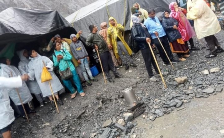 Orang-orang berdiri di luar tenda setelah hujan deras di dekat kuil suci gua Amarnath di Kashmir