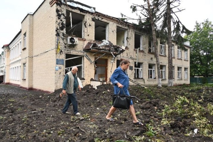 Penduduk setempat berjalan melewati sebuah bangunan yang rusak akibat penembakan di Chuhuiv, timur Kharkiv 