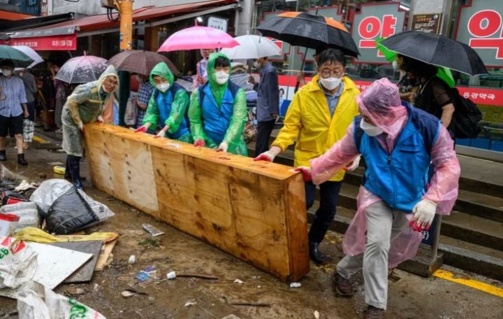 Pekerja membersihkan puing-puing di Pasar Namseong yang bersejarah di distrik Gangnam Seoul setelah hujan yang memecahkan rekor menyebabkan banjir parah [Anthony Wallace/ AFP]