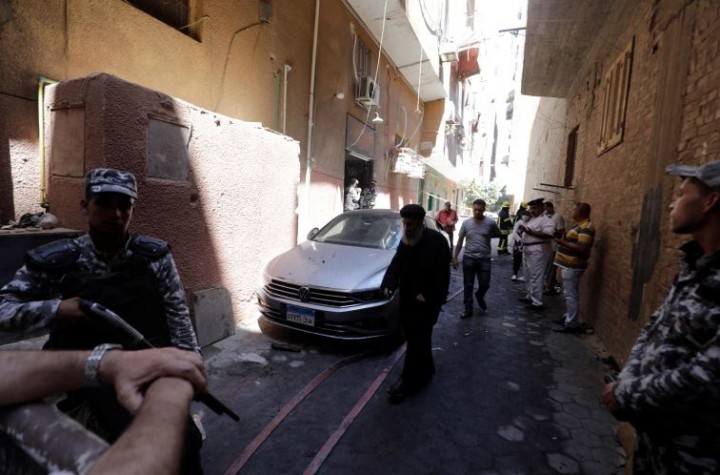 Orang-orang dan polisi berdiri di dekat lokasi kebakaran mematikan terjadi di gereja Abu Sifin di Giza [Mohamed Abd el-Ghany/Reuters]