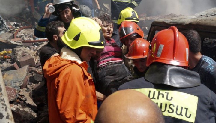 Petugas pemadam kebakaran mengevakuasi seorang wanita yang terluka dari kebakaran di pasar Surmalu di Yerevan [Foto Daniel Bolshakov/AP]