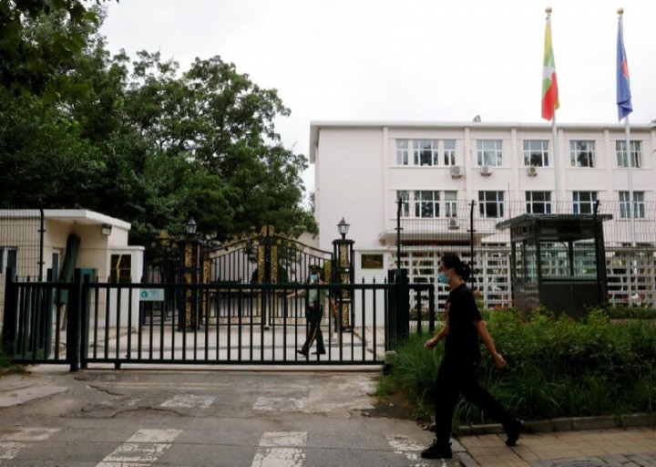 Seorang pria berjalan melewati seorang petugas polisi paramiliter yang berjaga di luar kedutaan Myanmar di Beijing, China, pada 8 Agustus 2022. Reuters
