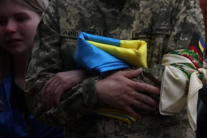 Ayah dari seorang tentara Ukraina yang tewas dalam aksi memegang bendera Ukrainanya selama upacara pemakaman di ibukota Kyiv [File: Leah Millis / Reuters]