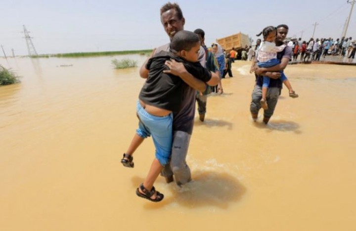 Orang-orang mengarungi air saat banjir di al-Managil di negara bagian Gezira, Sudan, 23 Agustus [Mohamed Nureldin Abdallah/Reuters]