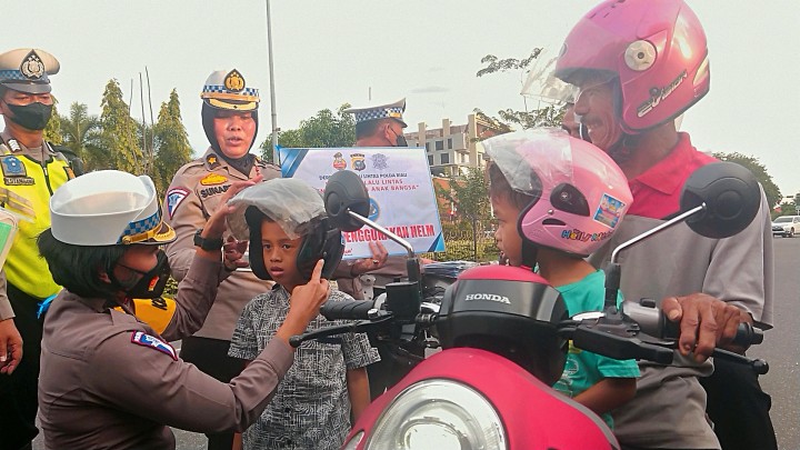 PS Kasubbid Kamsel Ditlantas Polda Riau, Kompol Birgitta Atvina memberikan helm pada anak-anak sebagai edukasi dalam berkendara. 