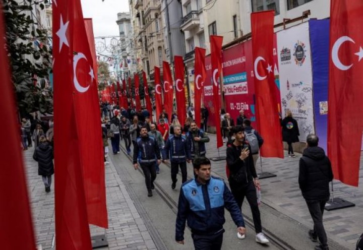 Orang-orang berjalan di sepanjang Istiklal Avenue yang dihiasi bendera Turki pada 14 November 2022, sehari setelah pengeboman mematikan [Umit Bektas/Reuters]
