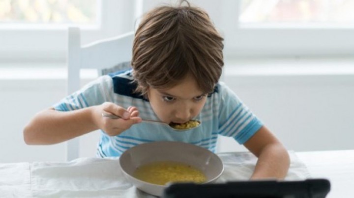 Ilustrasi Anak yang Makan Sambil Gawai. (Suara.com)