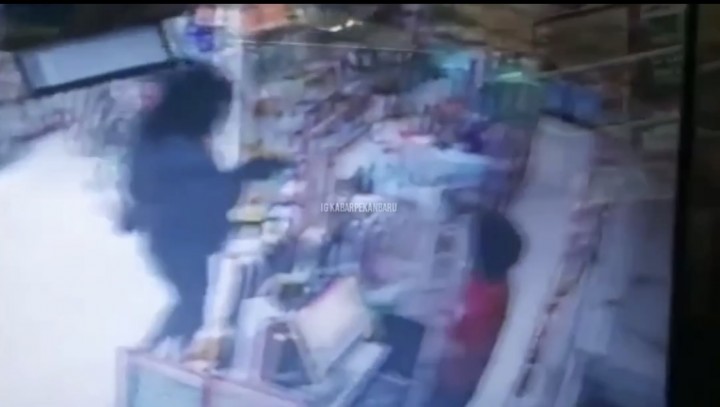 Tampak pelaku perampokan mencoba menodongkan senjata api ke karyawati retail.