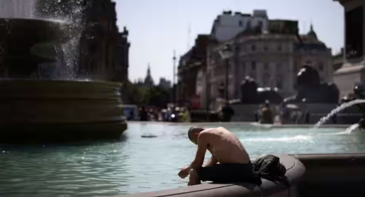 Seorang pria mendinginkan diri di air mancur selama gelombang panas, di Trafalgar Square di London /Reuters