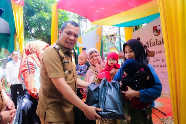 Pj Wali Kota Pekanbaru Muflihun menyerahkan bantuan kepada orang tua dengan anak berisiko stunting di acara Halalbihalal Kecamatan Bukit Raya, Selasa (9/5/2023). Foto: Istimewa.