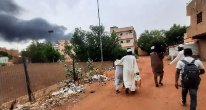 Asap membubung di atas bangunan saat orang-orang melarikan diri dengan beberapa barang, di Khartoum pada 10 Juni 2023 /AFP