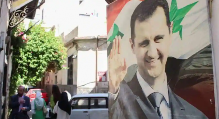 Orang-orang berjalan di dekat poster yang menggambarkan Presiden Suriah Bashar al-Assad di Damaskus, Suriah 19 Mei 2023 /Reuters