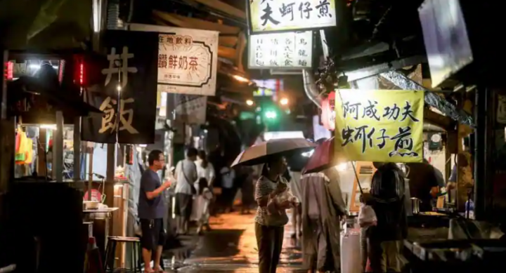 Seorang pelanggan (tengah) membeli makanan di pasar malam di pusat kota Yilan, setelah Topan Haikui mendarat di Taiwan timur pada 3 September 2023 /AFP