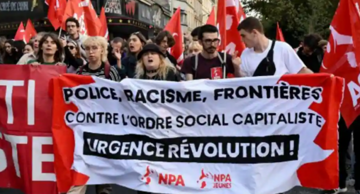 Orang-orang memegang spanduk NPA partai sayap kiri Prancis bertuliskan dalam bahasa Prancis 