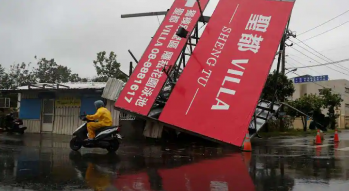 Seseorang dengan skuter melewati papan reklame yang jatuh setelah Topan Koinu melewati ujung selatan Taiwan, di Kenting pada 5 Oktober 2023 /Reuters