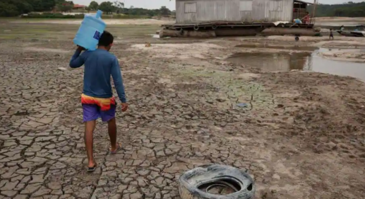 Di daerah kering dekat aliran Igarape do Taruma, yang mengalir ke sungai Rio Negro, seorang pria memegang sebotol air saat ketinggian air di pelabuhan sungai utama di hutan hujan Amazon Brasil mencapai titik terendah dalam lebih dari satu abad, yang mencakup setidaknya 121 tahun /Reuters
