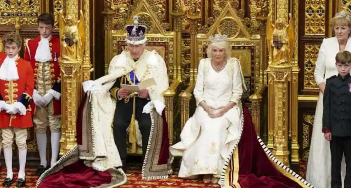 Ratu Inggris Camilla, mengenakan George IV State Diadem, duduk di samping Raja Inggris Charles III, mengenakan Imperial State Crown dan Jube of State, saat ia membacakan pidato Raja dari The Sovereign's Throne di ruang House of Lords, selama Pembukaan Parlemen Negara, di Gedung Parlemen, di London, 