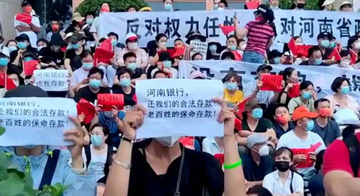 Demonstran memegang tanda-tanda selama protes atas pembekuan simpanan oleh beberapa bank berbasis pedesaan, di luar gedung People's Bank of China di Zhengzhou, provinsi Henan, China 10 Juli 2022 /Reuters