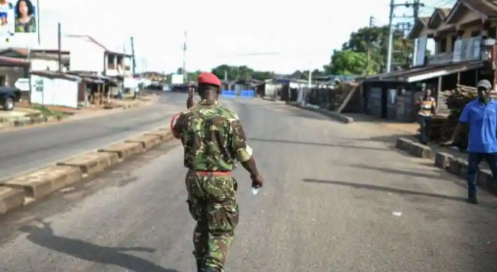 Seorang Prajurit dengan polisi militer Sierra Leone menyapa dan pria di sepanjang jalan kosong di Freetown pada 26 November 2023 /AFP