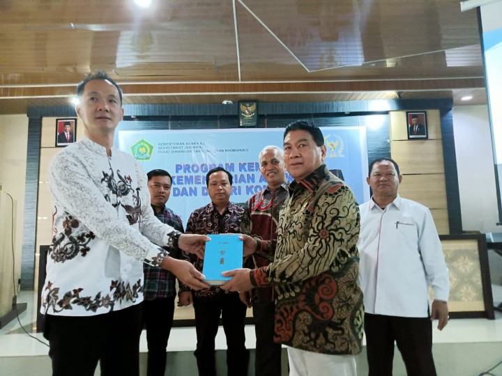 Anggota komisi VIII DPR RI Achmad menyerahkan kitab ke salah satu tokoh agama Konghucu Riau 