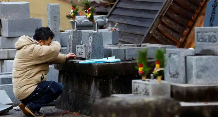 Seorang pria yang kehilangan rumahnya dalam gempa bereaksi ketika dia mengunjungi kuburan orang tuanya, yang diguncang oleh gempa, di Wajima, Jepang, 4 Januari 2024 /Reuters