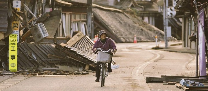 Potret Seorang Wanita Paruh Baya Menaiki Sepedanya di tengah Reruntuhan Rumah Akibat Gempa Jepang. (X/@Spinter998000)