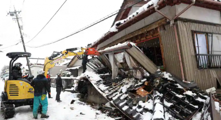 Gambar yang diambil pada 8 Januari 2024 menunjukkan sukarelawan menghancurkan sebagian rumah yang runtuh karena pemiliknya khawatir akan melukai orang yang lewat di kota Suzu, prefektur Ishikawa /AFP