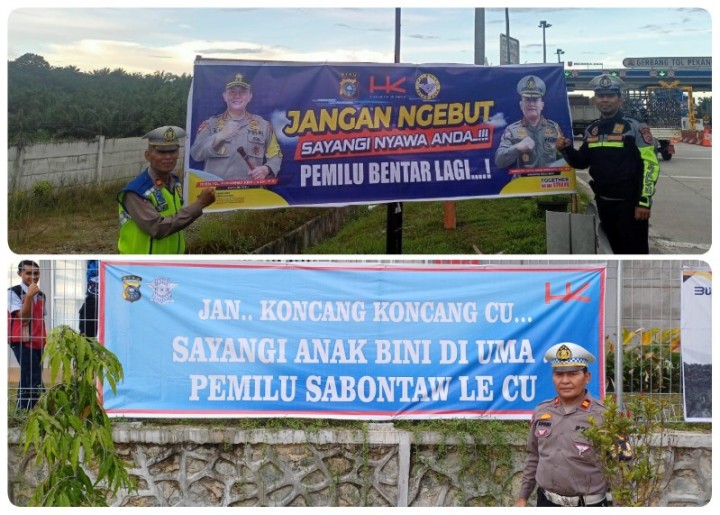 Petugas Ditlantas Polda Riau terlihat memasang spanduk pemilu damai di ruas Jalan tol