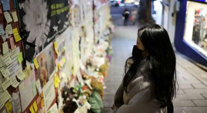 Seorang wanita berdoa sambil membaca pesan belasungkawa yang menempel di dinding gang sempit Itaewon tempat tragedi Halloween mematikan yang menewaskan lebih dari 150 orang pada Oktober terjadi, di Seoul, Korea Selatan, 18 Desember 2022 /Reuters