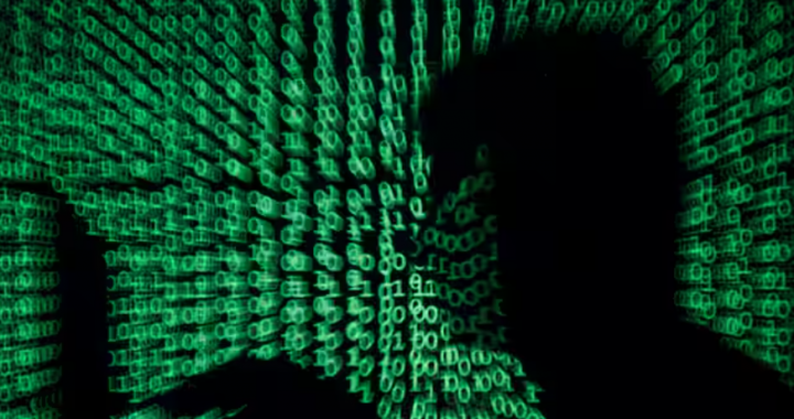 Seorang pria memegang komputer laptop sebagai kode cyber diproyeksikan pada dirinya dalam ilustrasi ini /Reuters
