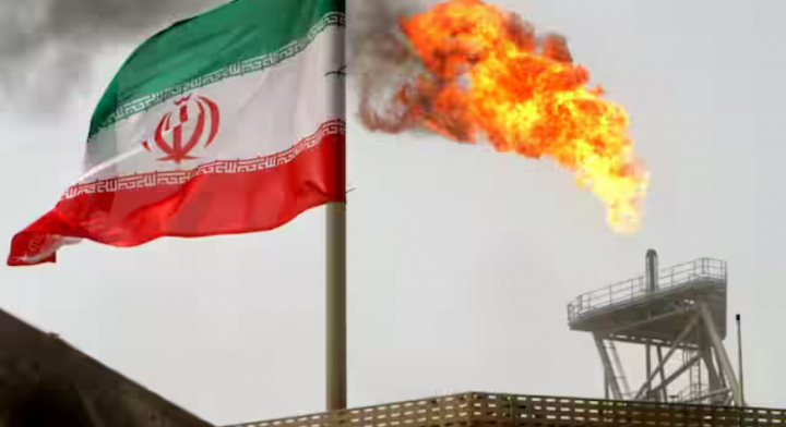 Suar gas pada platform produksi minyak terlihat di samping bendera Iran /Reuters