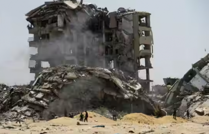 Warga Palestina berjalan melewati puing-puing bangunan tempat tinggal yang hancur akibat serangan Israel di Gaza /Reuters