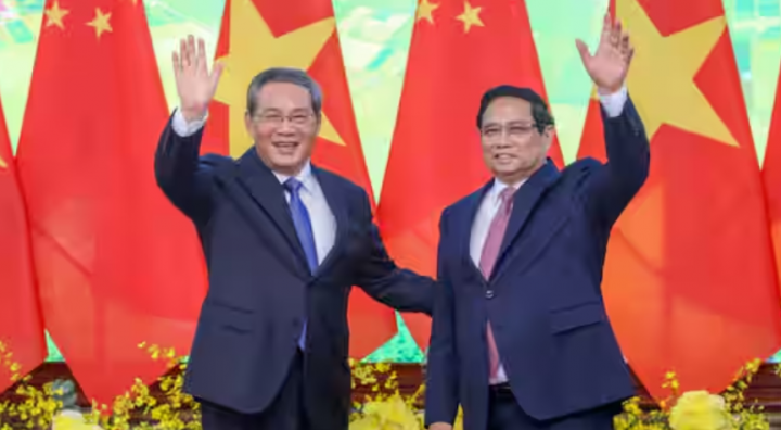 Perdana Menteri Vietnam Pham Minh Chinh (kanan) dan Perdana Menteri Tiongkok Li Qiang (kiri) melambaikan tangan saat mereka berpose untuk foto selama pertemuan di Kantor Pemerintah di Hanoi pada 13 Oktober 2024 /AFP