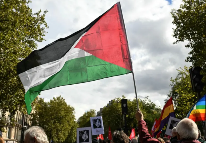 Seorang pengunjuk rasa mengibarkan bendera Palestina dalam pawai menuntut 