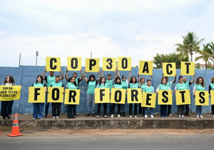 Anggota Greenpeace memegang spanduk yang menuntut tindakan untuk menyelamatkan hutan, di luar upacara pembukaan Pra-COP30, di Brasilia, Brasil/ AFP