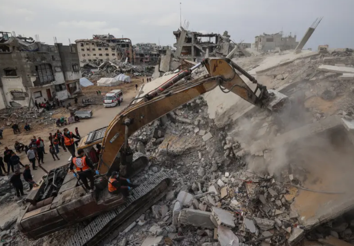 Personel Pertahanan Sipil menggunakan ekskavator untuk mencari sisa-sisa korban di reruntuhan bangunan yang hancur di kamp pengungsi Bureij, di Jalur Gaza tengah, pada 6 Desember 2025/ AFP